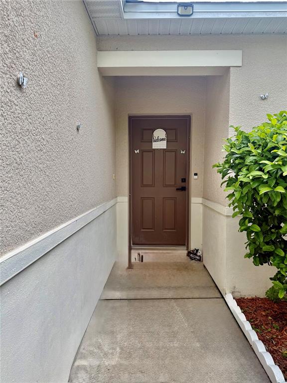 A brown front door is centered at the end of a concrete walkway — 4029 MARINA ISLE DRIVE, KISSIMMEE, FL