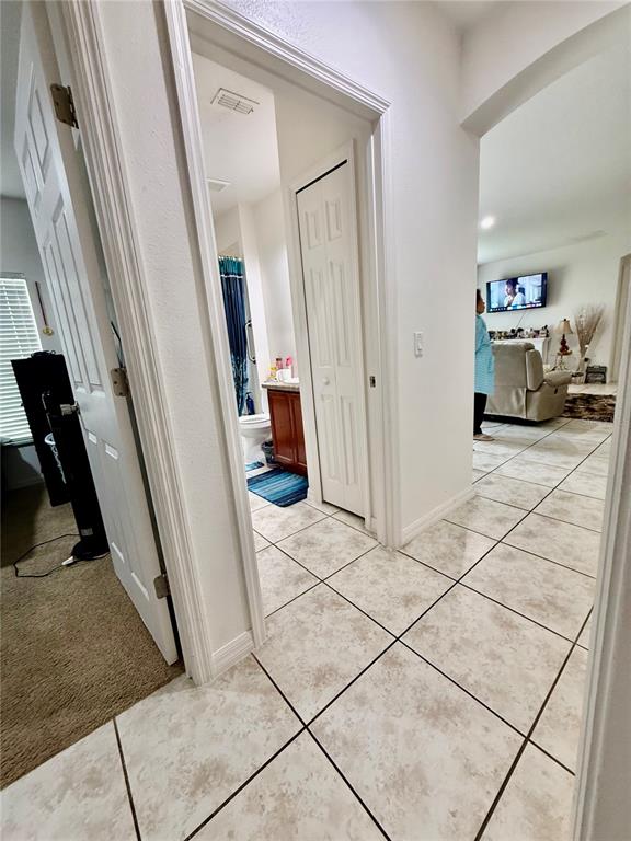 A tiled hallway leads to a bathroom and an open living area with a television — 4029 MARINA ISLE DRIVE, KISSIMMEE, FL