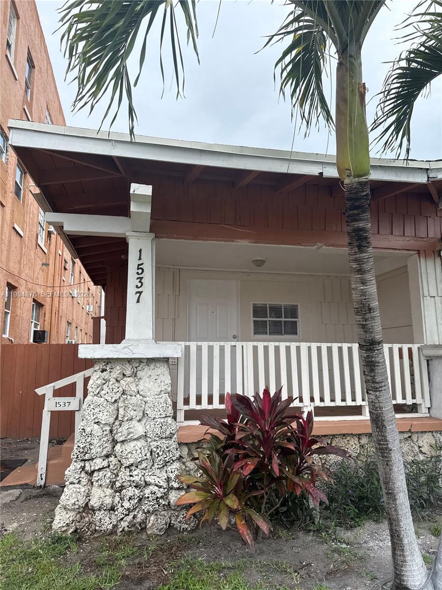 A covered porch features a stone pillar, white railing, and a palm tree in front — 1545 NW 1st St # 1537, Miami FL 33125, MIAMI, FL
