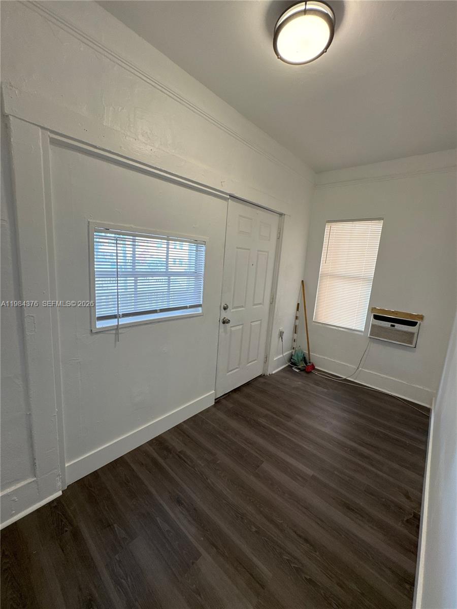 A room with dark wood-look flooring, white walls, two windows with blinds, and an air conditioner — 1545 NW 1st St # 1537, Miami FL 33125, MIAMI, FL