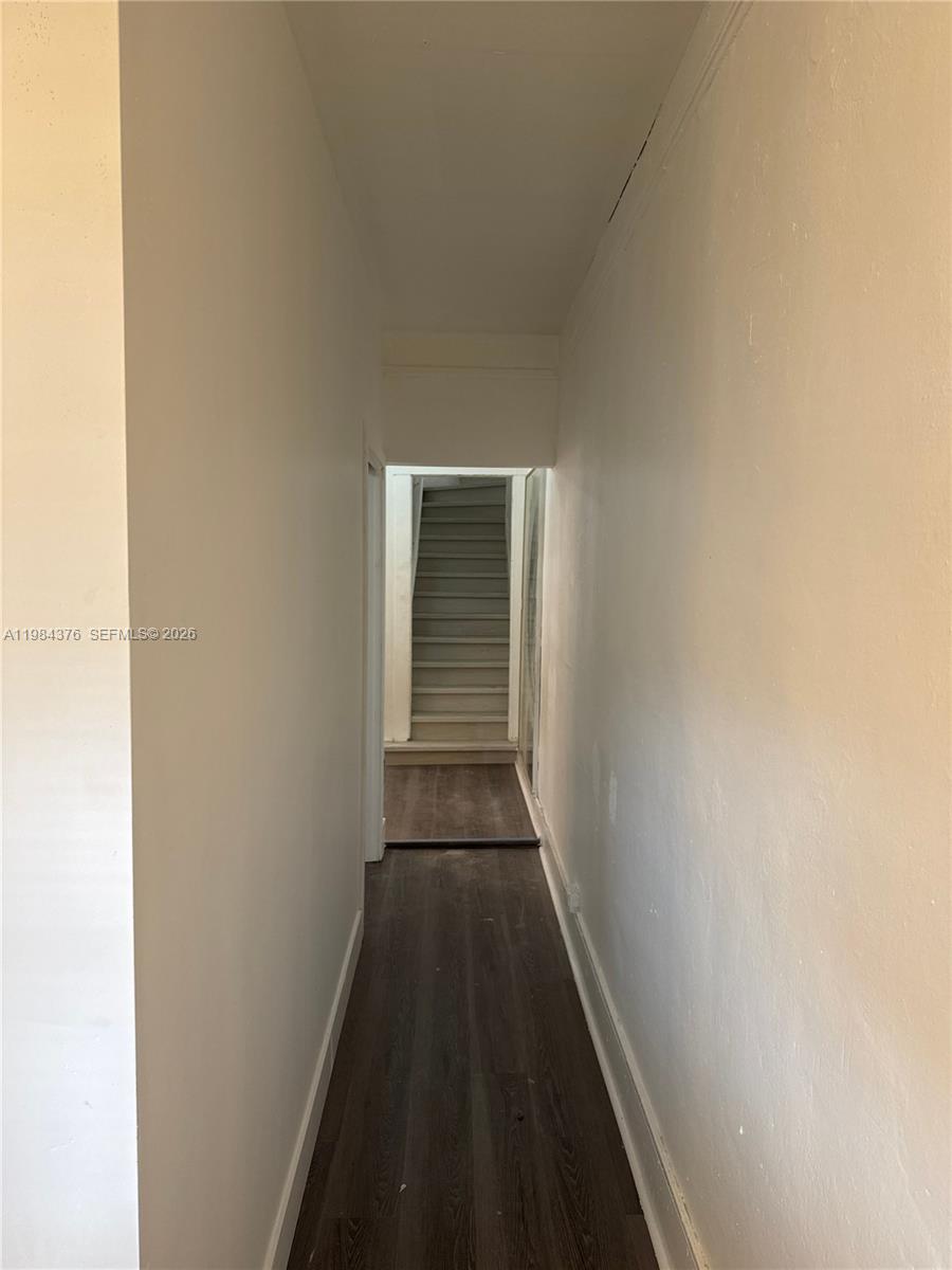 A narrow hallway with dark wood-look flooring leads to a staircase — 1545 NW 1st St # 1537, Miami FL 33125, MIAMI, FL
