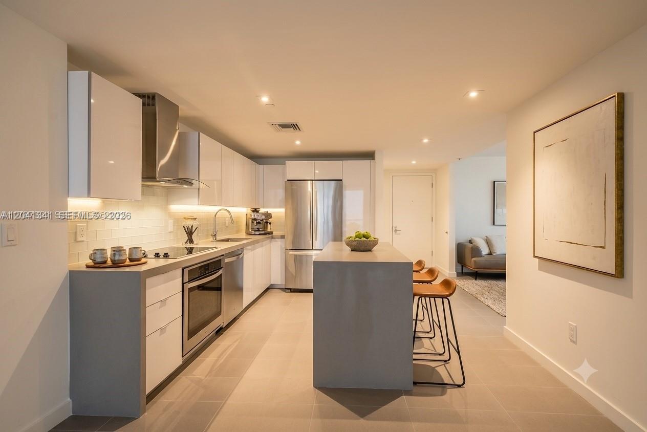 A modern kitchen features white cabinetry, stainless steel appliances, and a gray central island — 1600 NE 1st Ave # 1401, Miami FL 33132, MIAMI, FL