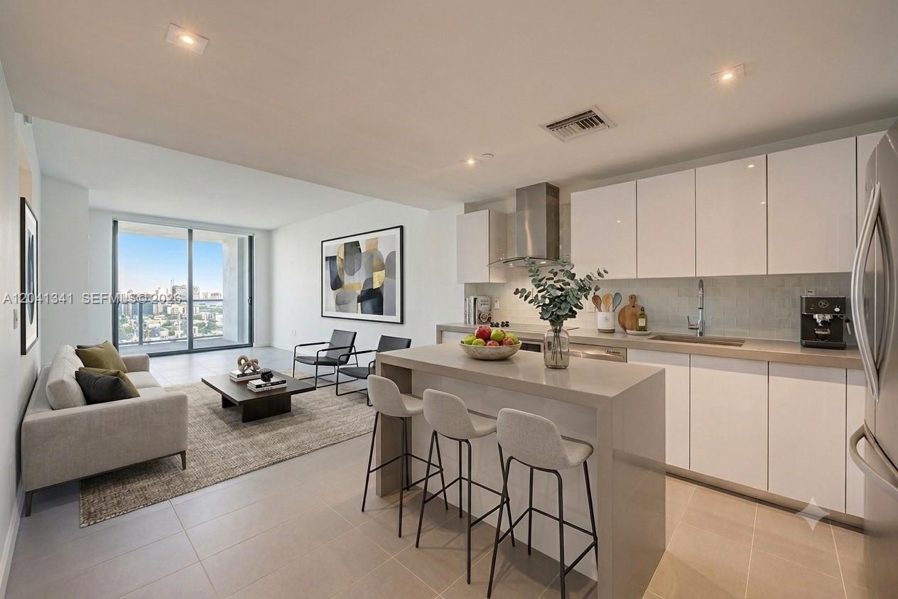 A modern open-concept kitchen and living area with white cabinets, a stone island, and balcony — 1600 NE 1st Ave # 1401, Miami FL 33132, MIAMI, FL