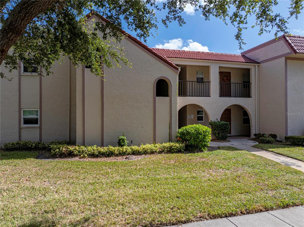 A two-story apartment building features stucco walls, a red tile roof, and arched entryways — 9700 STARKEY ROAD UNIT 312, SEMINOLE, FL