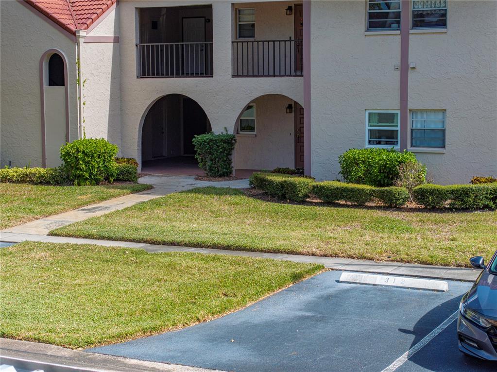 A two-story apartment building features arched entryways, balconies, and a paved parking space — 9700 STARKEY ROAD UNIT 312, SEMINOLE, FL