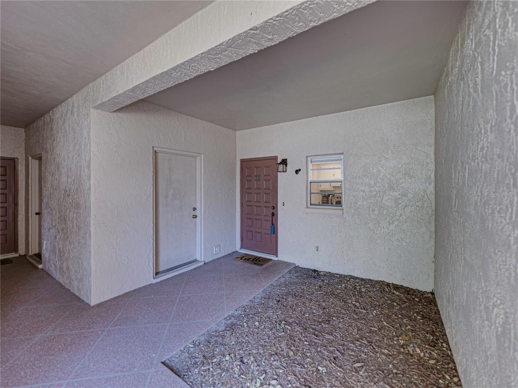 A covered entryway features a brown front door, a side door, and a small window — 9700 STARKEY ROAD UNIT 312, SEMINOLE, FL