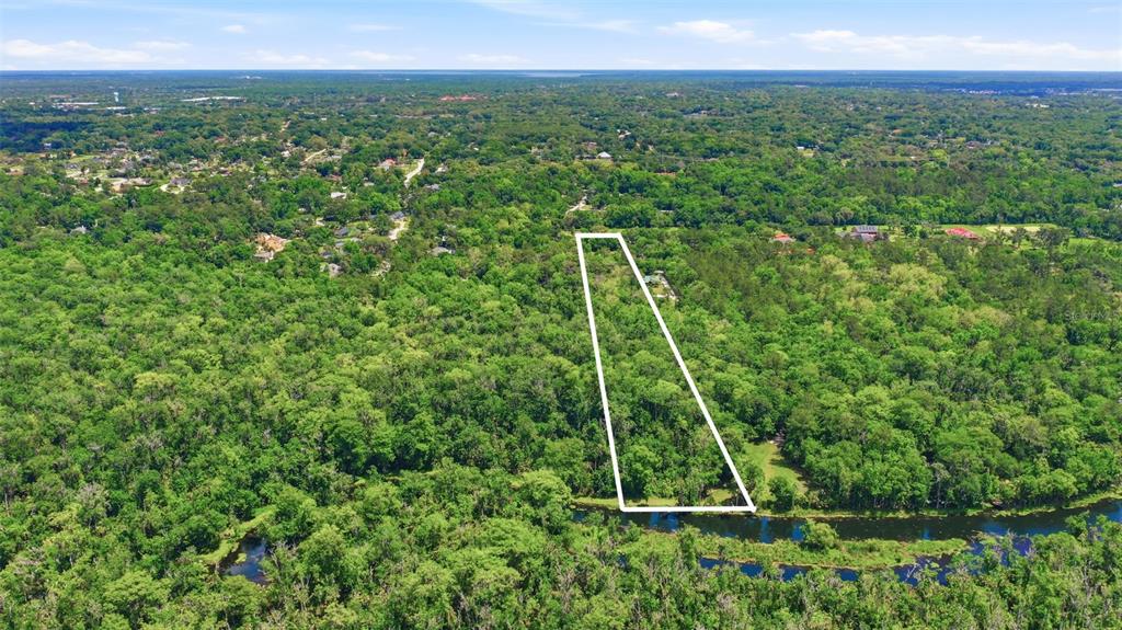 An aerial view shows a rectangular plot of land outlined in white bordering a river — DELK ROAD, LONGWOOD, FL