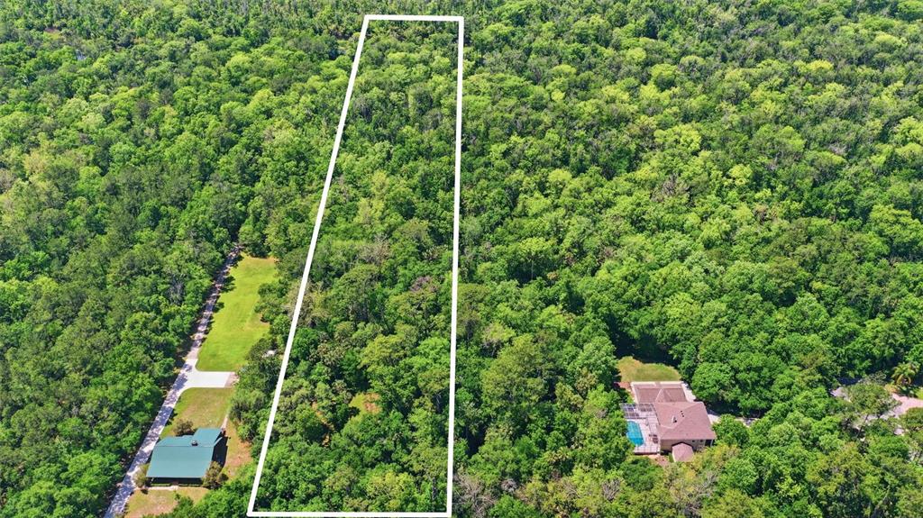 An aerial view shows a rectangular plot of land outlined in white amidst dense forest — DELK ROAD, LONGWOOD, FL