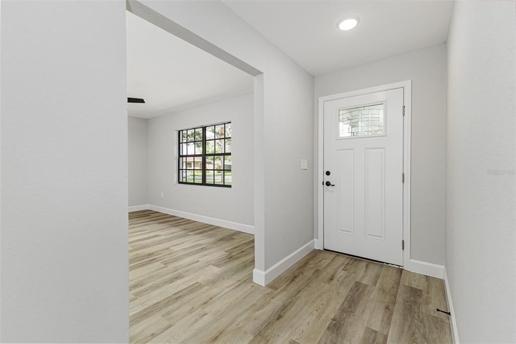 A modern kitchen features white cabinets, stainless steel appliances, and light wood-look flooring — 527 PRINCESS PLACE, LAKELAND, FL