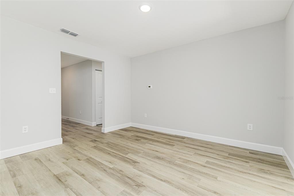 An empty room with light gray walls, wood-look flooring, two grid-pane windows, and a ceiling fan — 527 PRINCESS PLACE, LAKELAND, FL