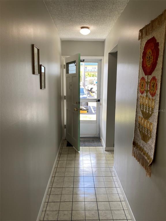 A tiled hallway leads to an open front door revealing a view of a parking lot — 5660 80TH STREET N UNIT B107, ST PETERSBURG, FL