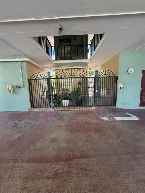 A ground-level covered parking area features a gated entrance leading to a building elevator — 180 SE 20TH AVENUE UNIT 303, DEERFIELD BEACH, FL