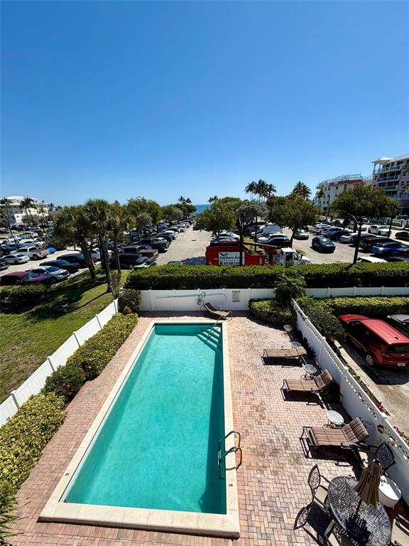 An outdoor swimming pool is surrounded by a brick patio and lounge chairs — 180 SE 20TH AVENUE UNIT 303, DEERFIELD BEACH, FL