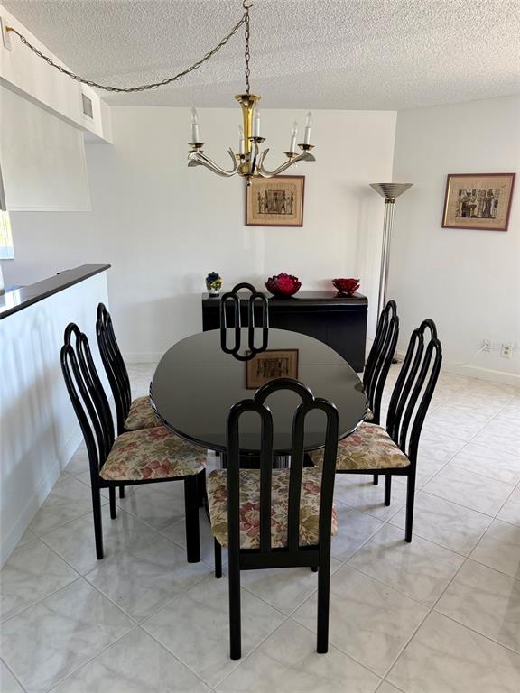 A dining room features a black oval table, six chairs with floral cushions, and a chandelier — 180 SE 20TH AVENUE UNIT 303, DEERFIELD BEACH, FL