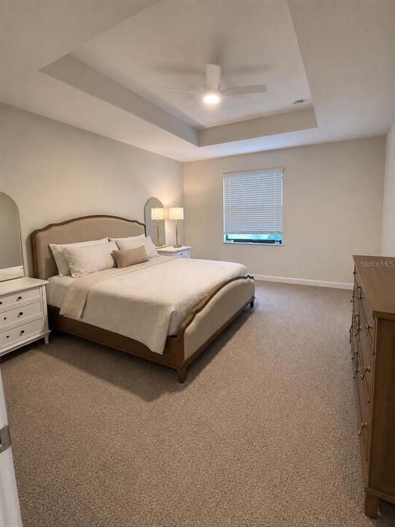 A bedroom features a tray ceiling, a bed with a wooden frame, and carpeted flooring — 1270 ROYAL ST GEORGE BOULEVARD, DAVENPORT, FL