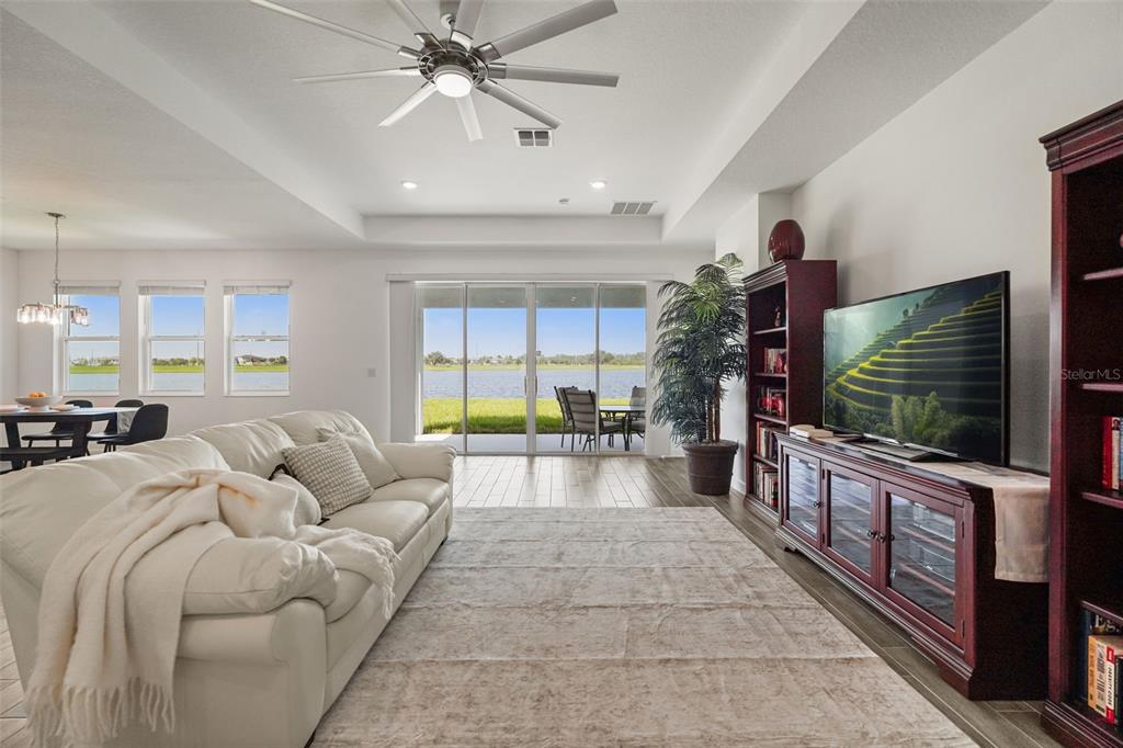 A living room with a white sofa, television, and sliding glass doors overlooking a lake — 3020 ELLA WAY, ST CLOUD, FL