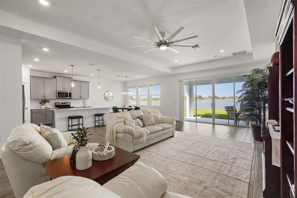 An open-concept living room and kitchen featuring white sofas, gray cabinetry, and sliding glass doors — 3020 ELLA WAY, ST CLOUD, FL