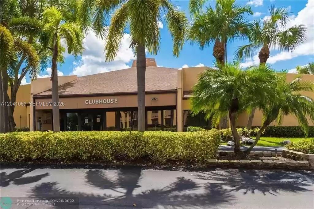 A tan clubhouse building is surrounded by palm trees and a manicured hedge — 6870 Royal Palm Blvd # 111M, Margate FL 33063, MARGATE, FL
