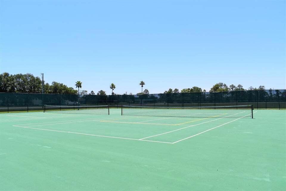 A green outdoor tennis court with a net and a surrounding chain-link fence — Tbd Azalea Drive, FL 33855, FL