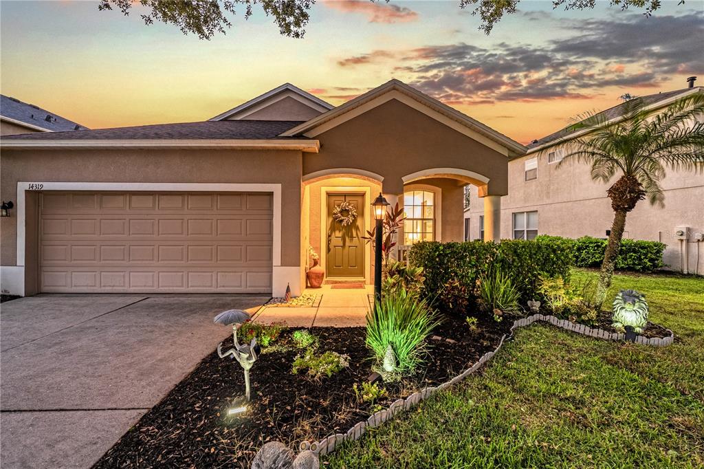 A single-story house exterior features a two-car garage, a covered entryway, and landscaped front yard — 14319 GNATCATCHER TERRACE, LAKEWOOD RANCH, FL
