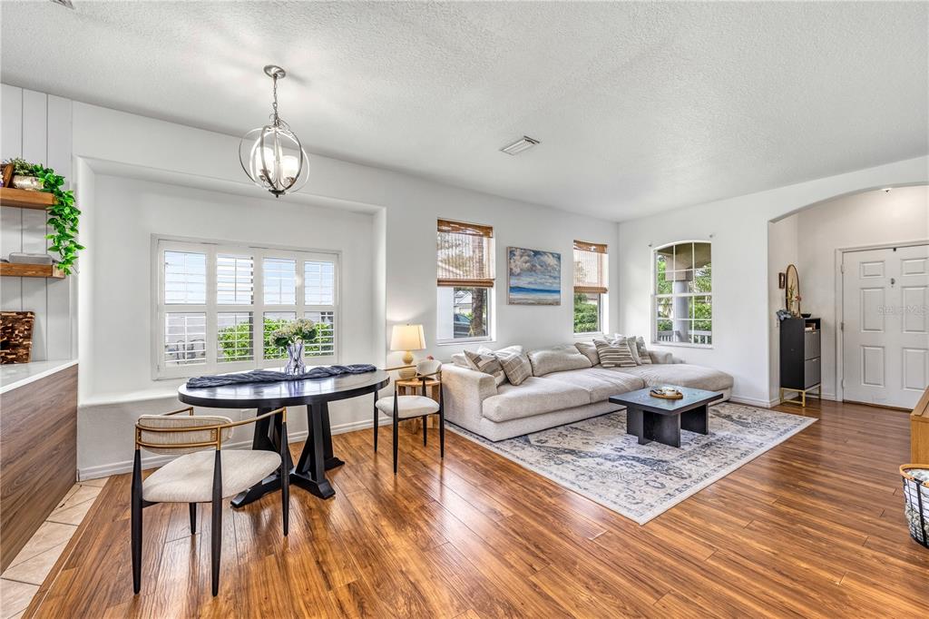 A living and dining area features wood flooring, a sectional sofa, and a round table — 14319 GNATCATCHER TERRACE, LAKEWOOD RANCH, FL