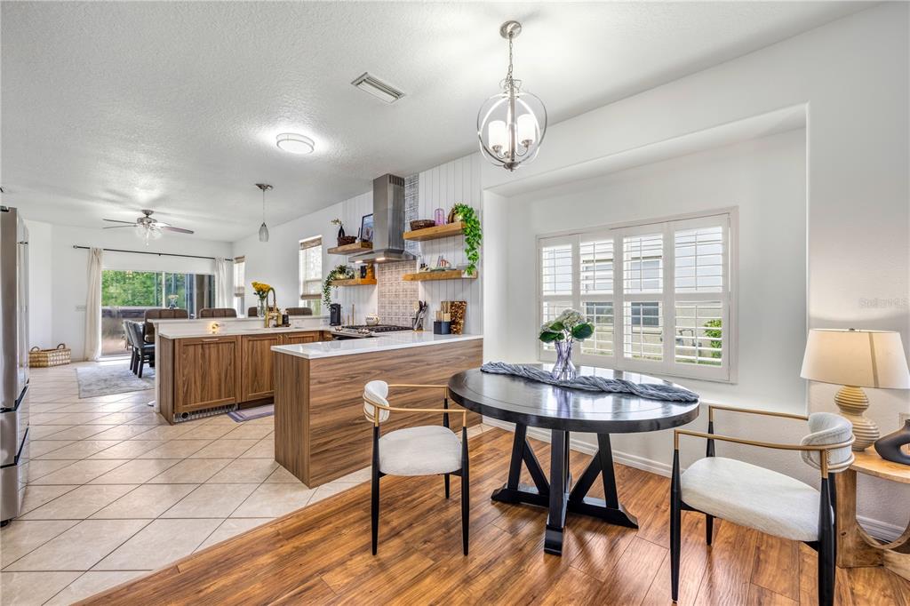 A kitchen and dining area featuring wood cabinetry, a round table, and tile flooring — 14319 GNATCATCHER TERRACE, LAKEWOOD RANCH, FL