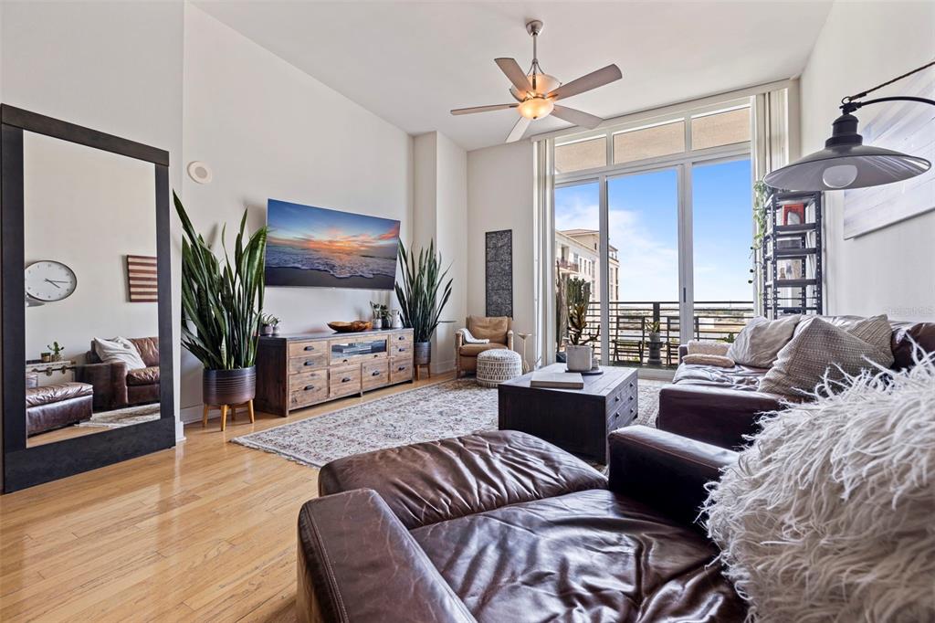 A living room features leather furniture, a large mirror, a television, and a balcony view — 1208 E KENNEDY BOULEVARD UNIT 831, TAMPA, FL