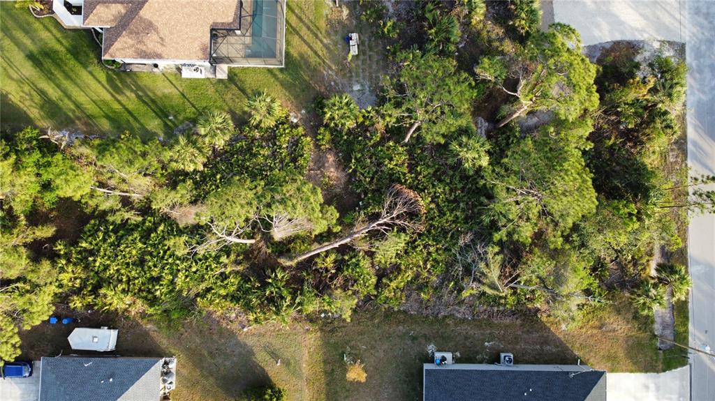 An aerial view shows a wooded, undeveloped residential lot situated between two houses — SPARKLE LANE, NORTH PORT, FL