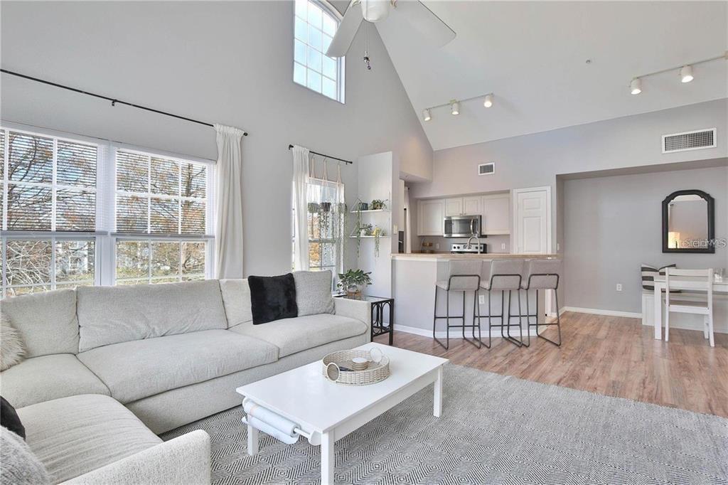 A living room with a vaulted ceiling, sectional sofa, and an open kitchen with bar seating — 5570 ROSEHILL ROAD UNIT 204, SARASOTA, FL