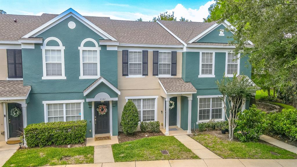 A row of three attached townhomes with teal and tan stucco exteriors and shingled roofs — 5338 HAWKSTONE DRIVE, SANFORD, FL