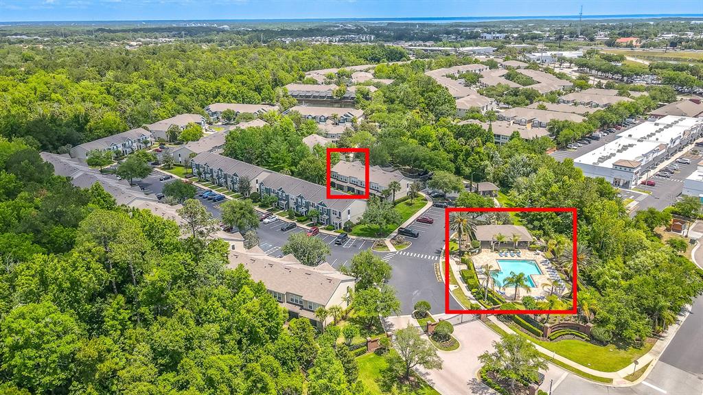 An aerial view shows a residential apartment complex with a swimming pool and surrounding trees — 5338 HAWKSTONE DRIVE, SANFORD, FL