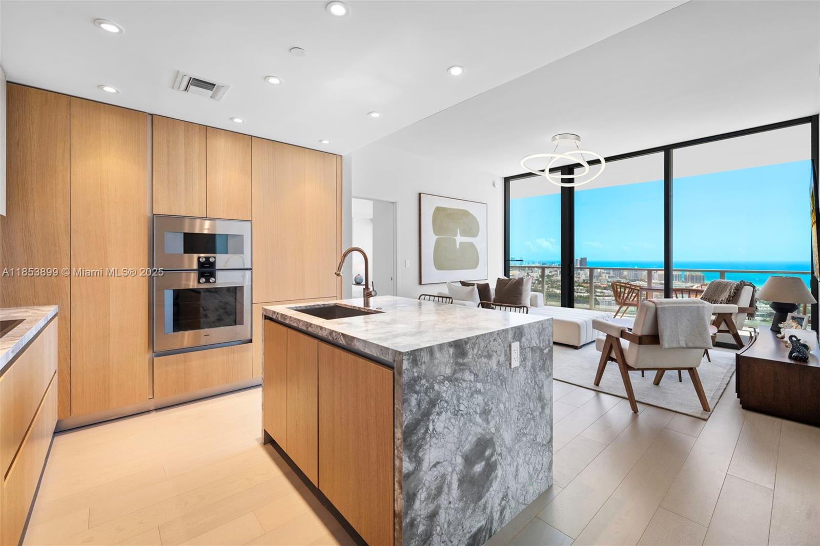 A modern kitchen with light wood cabinetry and a marble island overlooks a coastal view — 500 alton  rd # 3604, Miami Beach FL 33139, MIAMI BEACH, FL