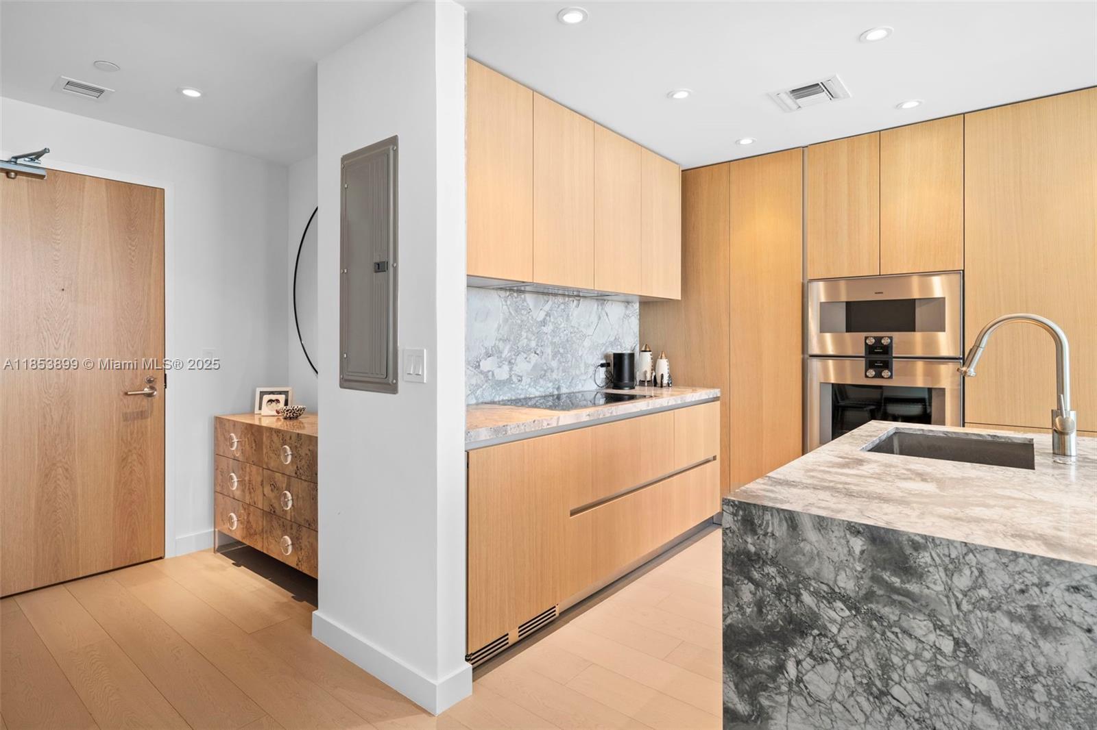 A modern kitchen features light wood cabinetry, marble countertops, and stainless steel appliances — 500 alton  rd # 3604, Miami Beach FL 33139, MIAMI BEACH, FL