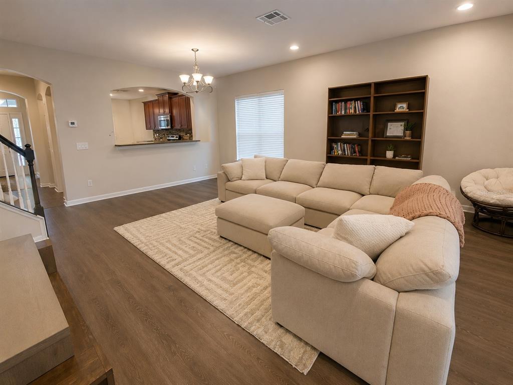 A tiled hallway features an arched entryway, a long white bench, and a staircase beyond — 7717 TANGLE BROOK BOULEVARD, GIBSONTON, FL