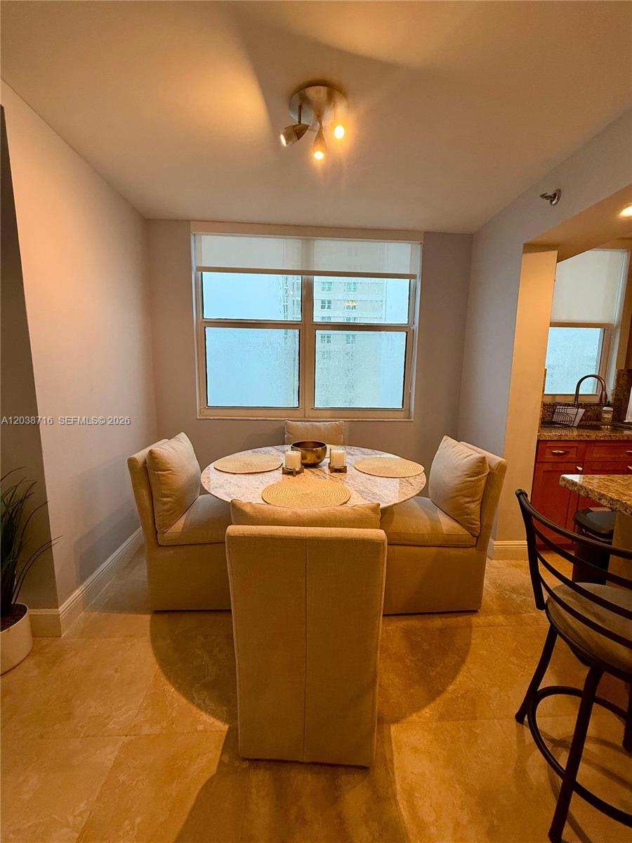 A dining area features a round marble table with four upholstered chairs and tile flooring — 770 Claughton Island Dr # 2016, Miami FL 33131, MIAMI, FL