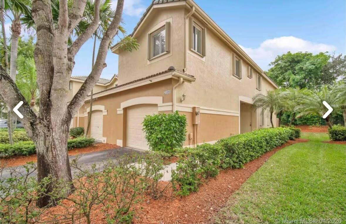 A two-story tan stucco townhouse with a garage and a manicured hedge in front — 2166 Hacienda Terrace, Weston FL 33327, WESTON, FL