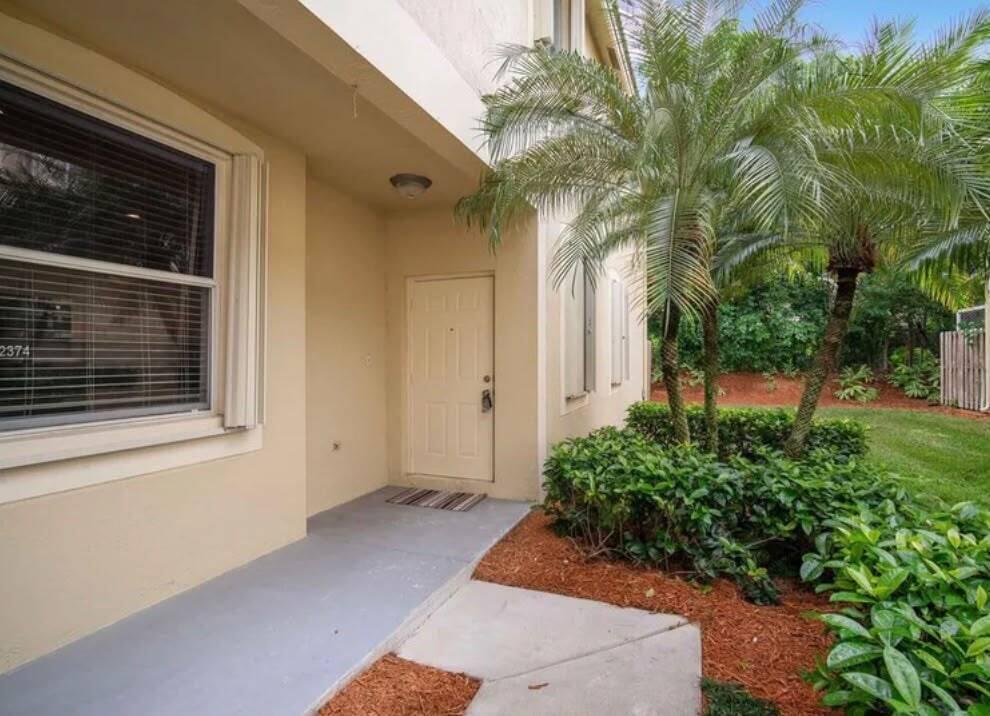 A tan exterior wall features a front door, a window, and a small concrete porch — 2166 Hacienda Terrace, Weston FL 33327, WESTON, FL