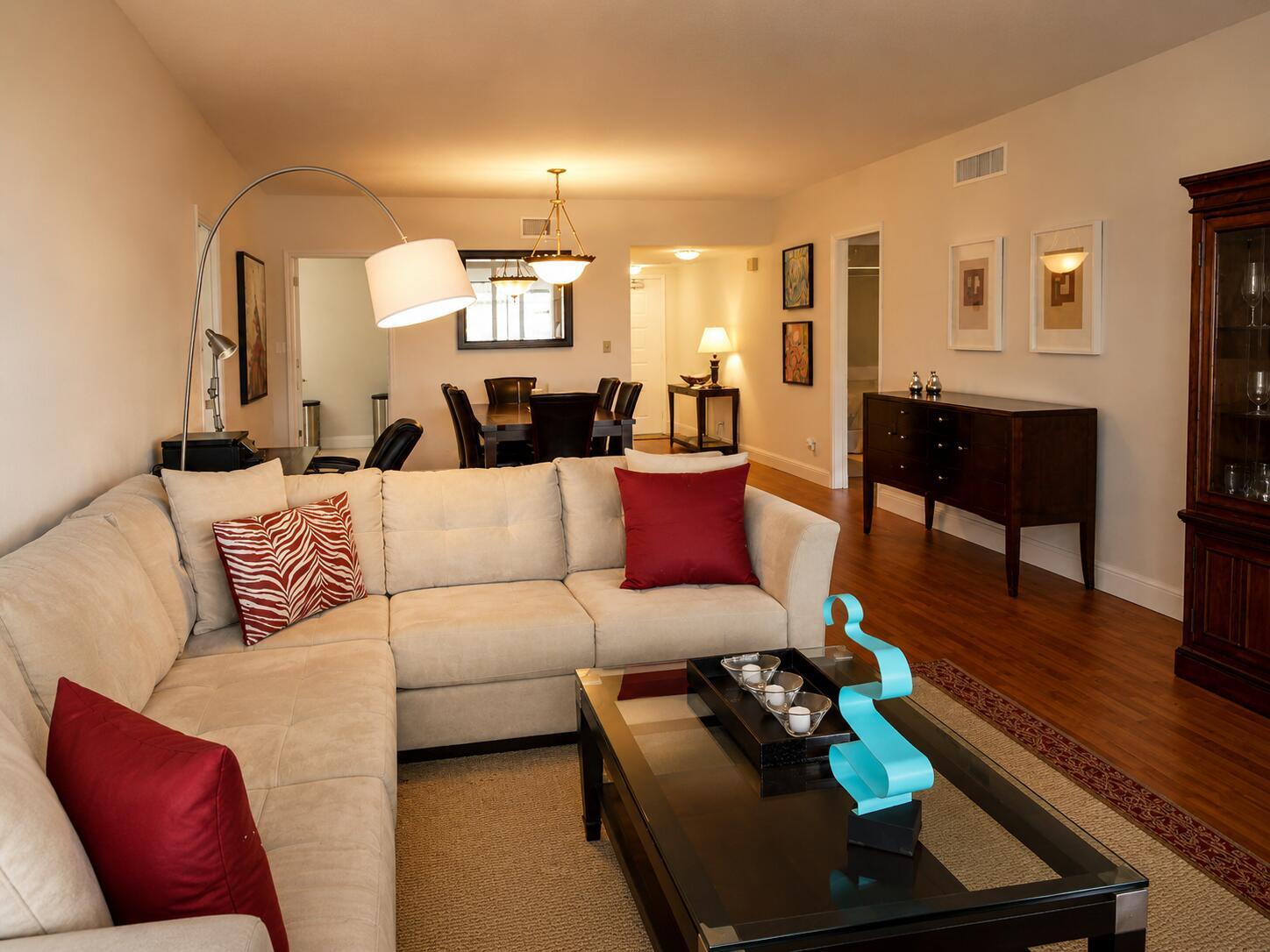 A living room with a beige sectional sofa, glass coffee table, and hardwood flooring — 804 Cypress Boulevard # 104, Pompano Beach FL 33069, POMPANO BEACH, FL