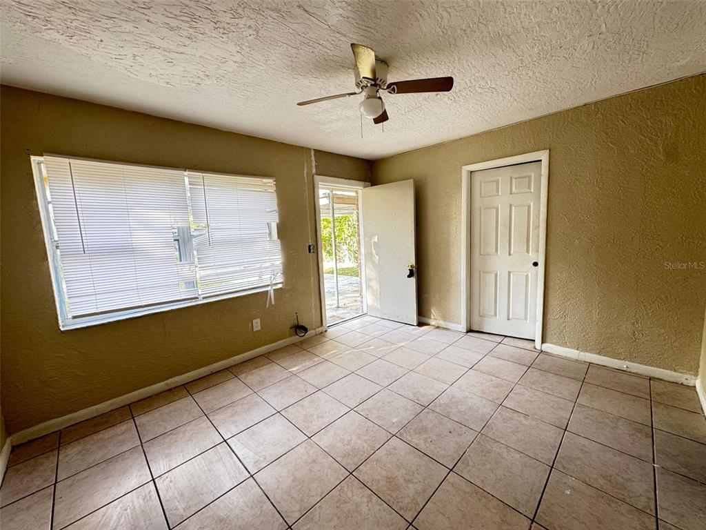 A room with beige textured walls, tiled flooring, a ceiling fan, and an exterior door — 1209 CARLSBAD PLACE, ORLANDO, FL