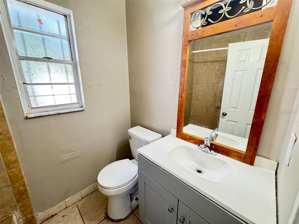 A bathroom features a gray vanity, a wooden-framed mirror, a toilet, and a window — 1209 CARLSBAD PLACE, ORLANDO, FL