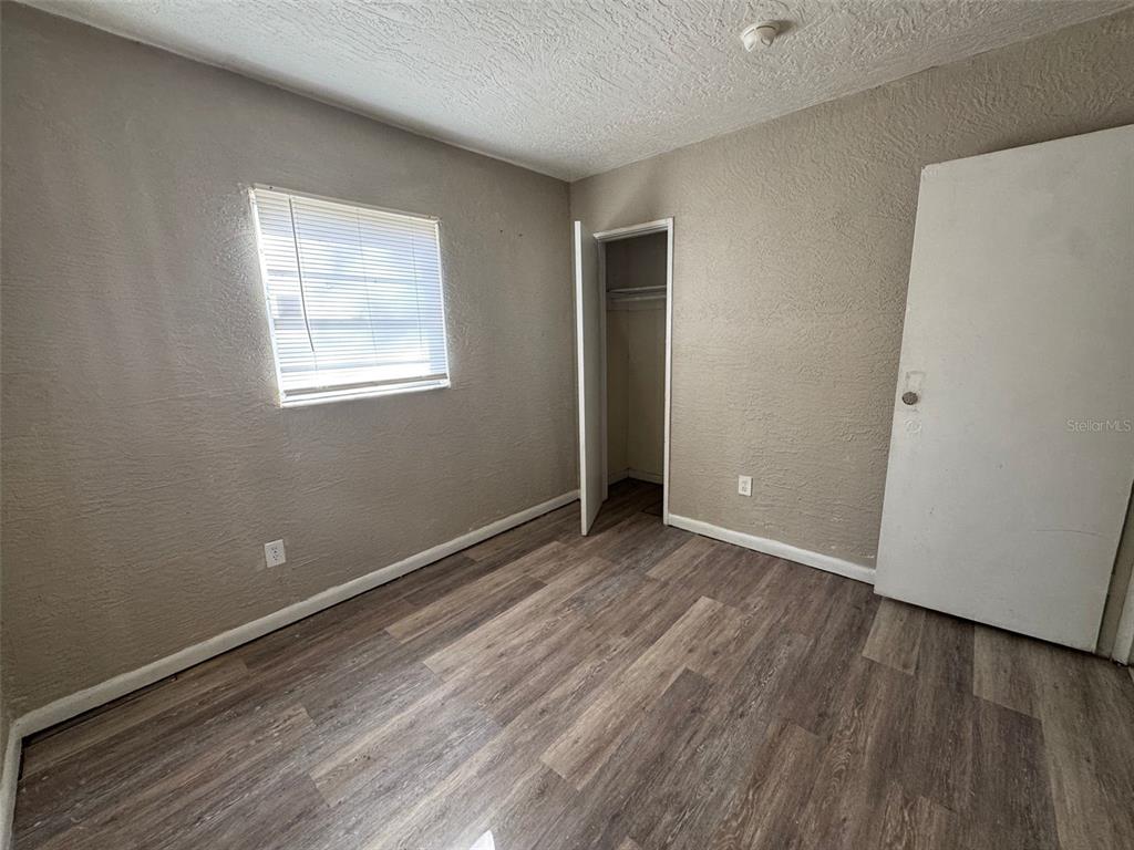 An empty bedroom features light-colored walls, wood-look flooring, a window with blinds, and a closet — 1209 CARLSBAD PLACE, ORLANDO, FL