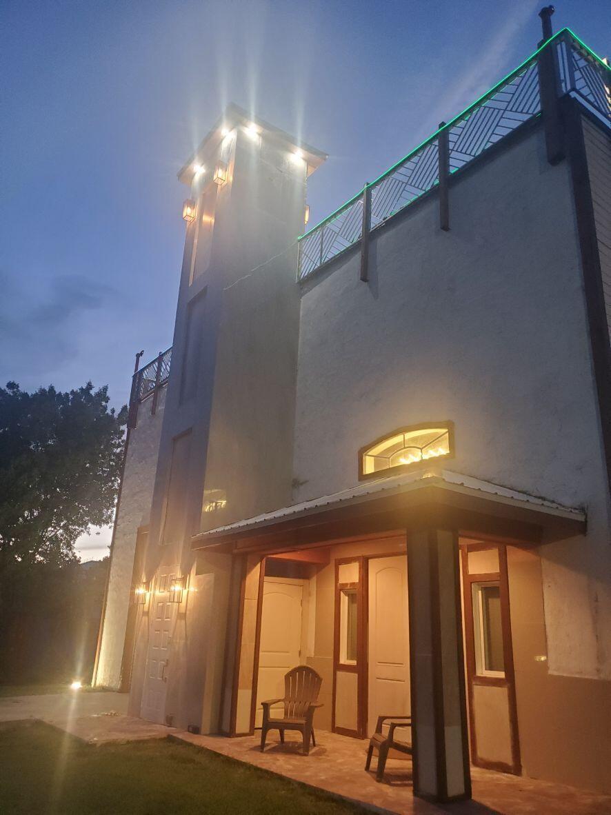A two-story building exterior at dusk featuring a tall tower, porch, and illuminated windows — 16825 89th Place N, FL 33470, FL