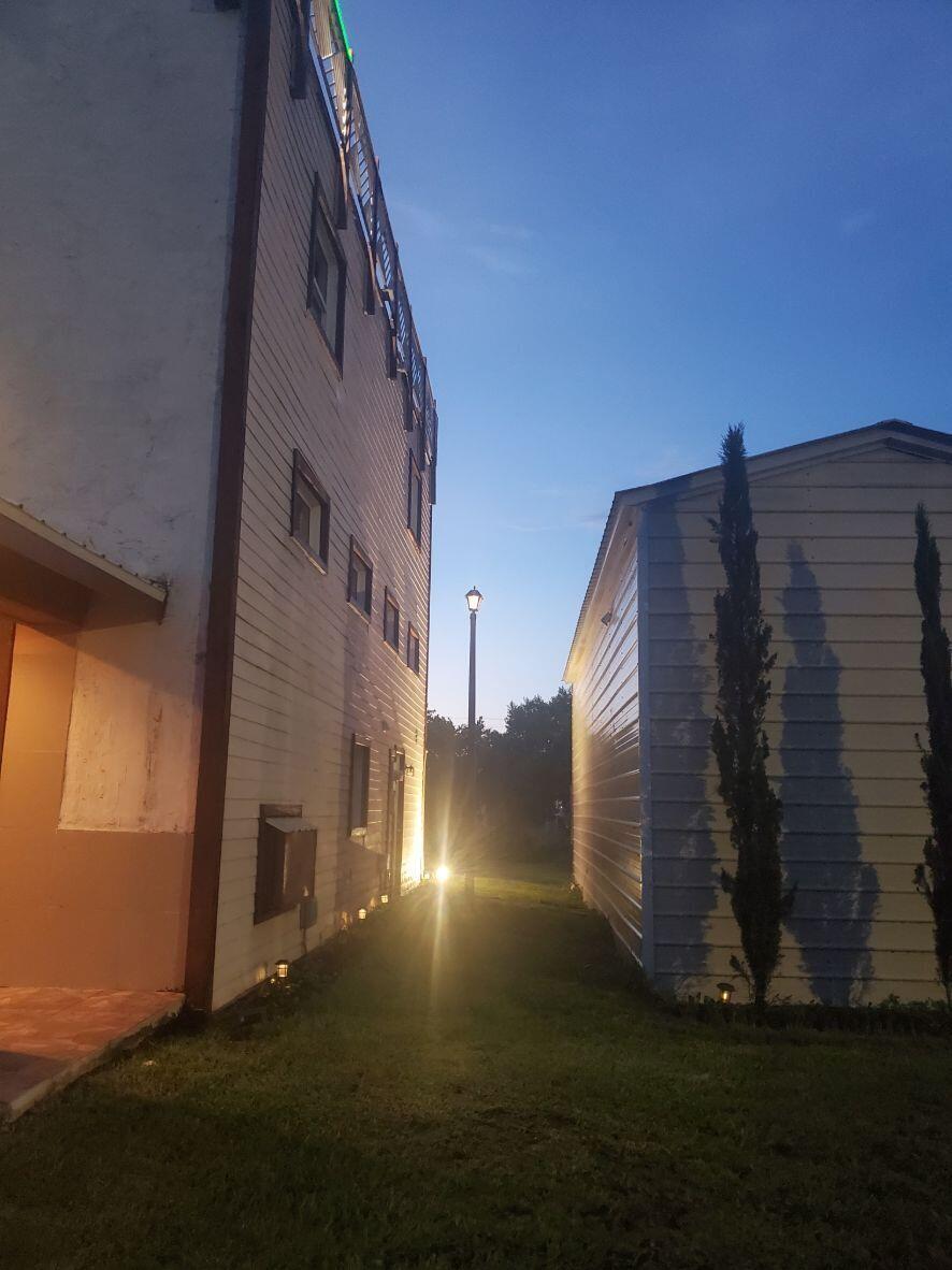 A narrow grassy path sits between two light-colored buildings illuminated by a single street lamp — 16825 89th Place N, FL 33470, FL