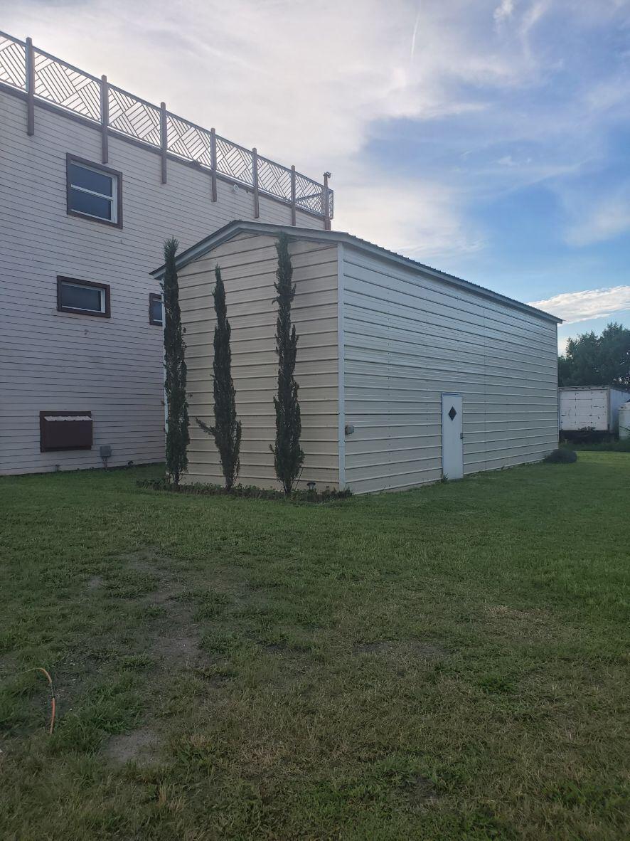 A beige metal storage building stands next to a multi-story house with a lattice fence — 16825 89th Place N, FL 33470, FL