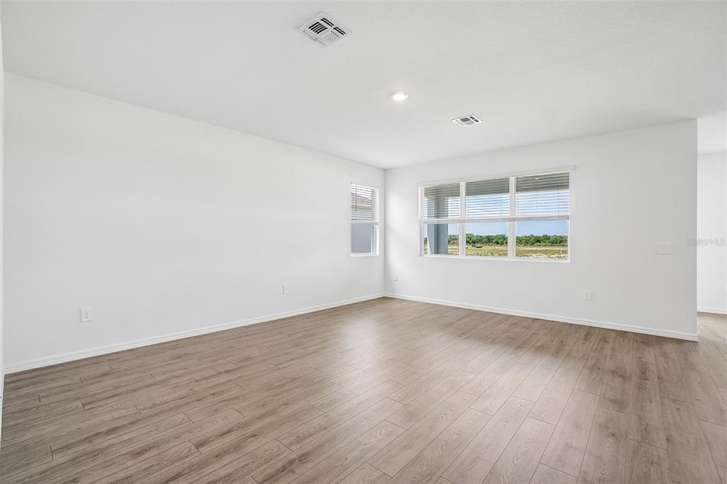 An empty room with white walls, wood-look flooring, and windows overlooking a grassy field — 4672 BARBERRY AVENUE, LAKELAND, FL