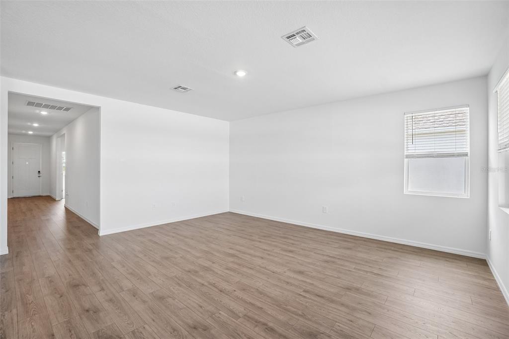 An empty room with white walls, light wood-look flooring, and a single window — 4672 BARBERRY AVENUE, LAKELAND, FL