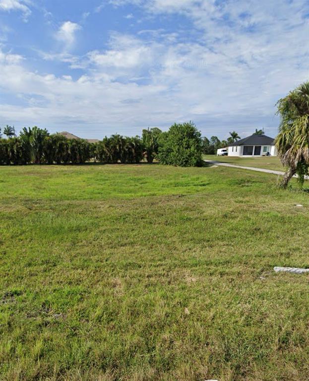 A vacant, grassy lot with a line of trees and a house in the distance — 113 WHITE MARSH LANE, ROTONDA WEST, FL