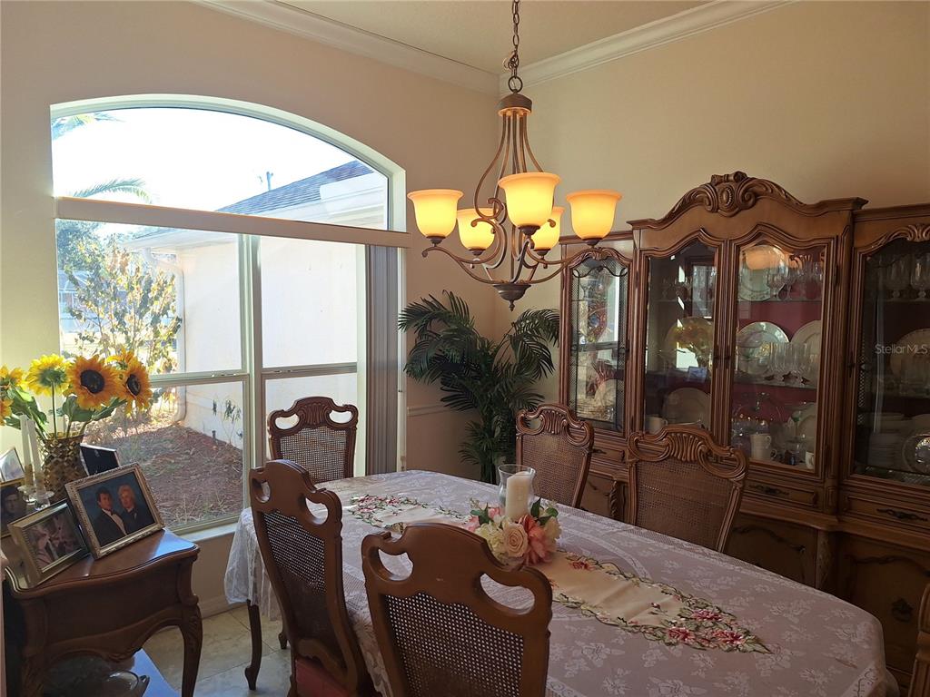 A dining room features a wooden hutch, a chandelier, and a table with floral decor — 48 WATERS DRIVE, PALM COAST, FL