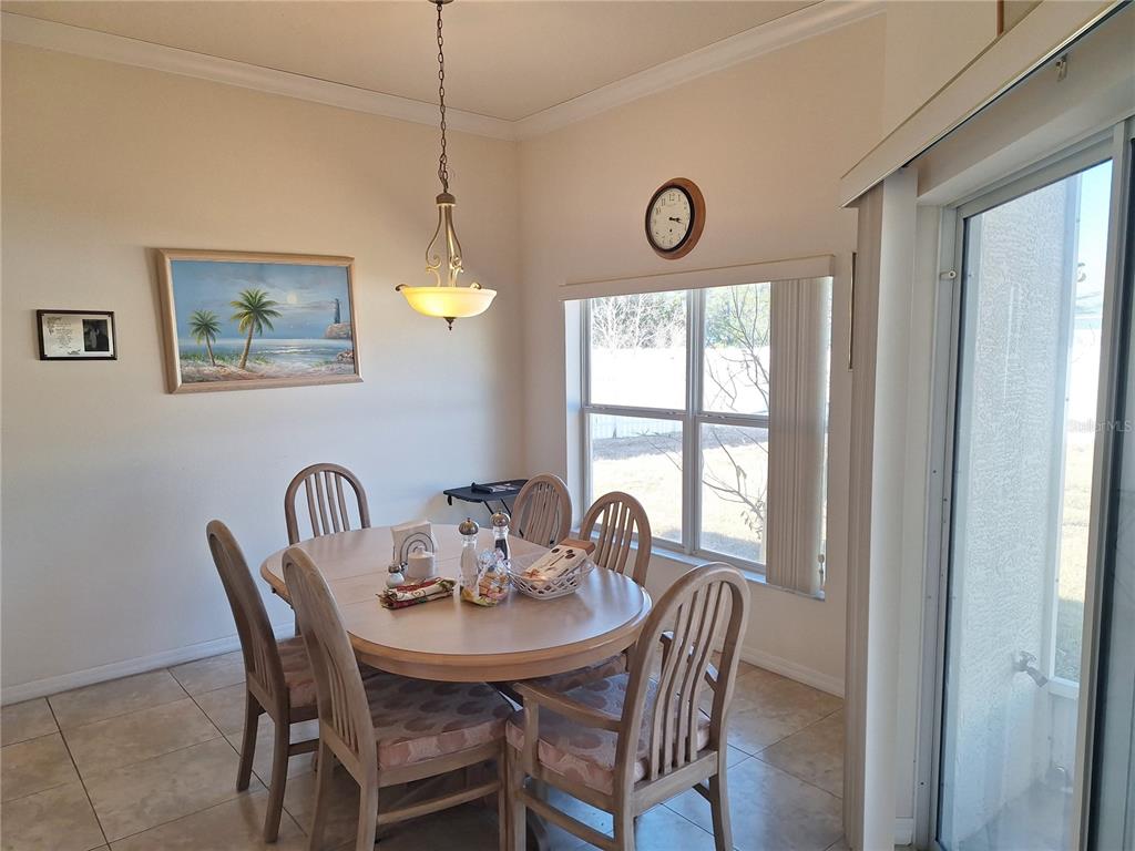A dining area features a wooden table with six chairs, a pendant light, and tile flooring — 48 WATERS DRIVE, PALM COAST, FL