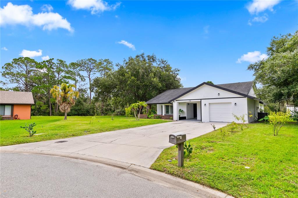 A white single-story house with a garage and a concrete driveway sits on a lawn — 714 DIVOT LANE, POINCIANA, FL